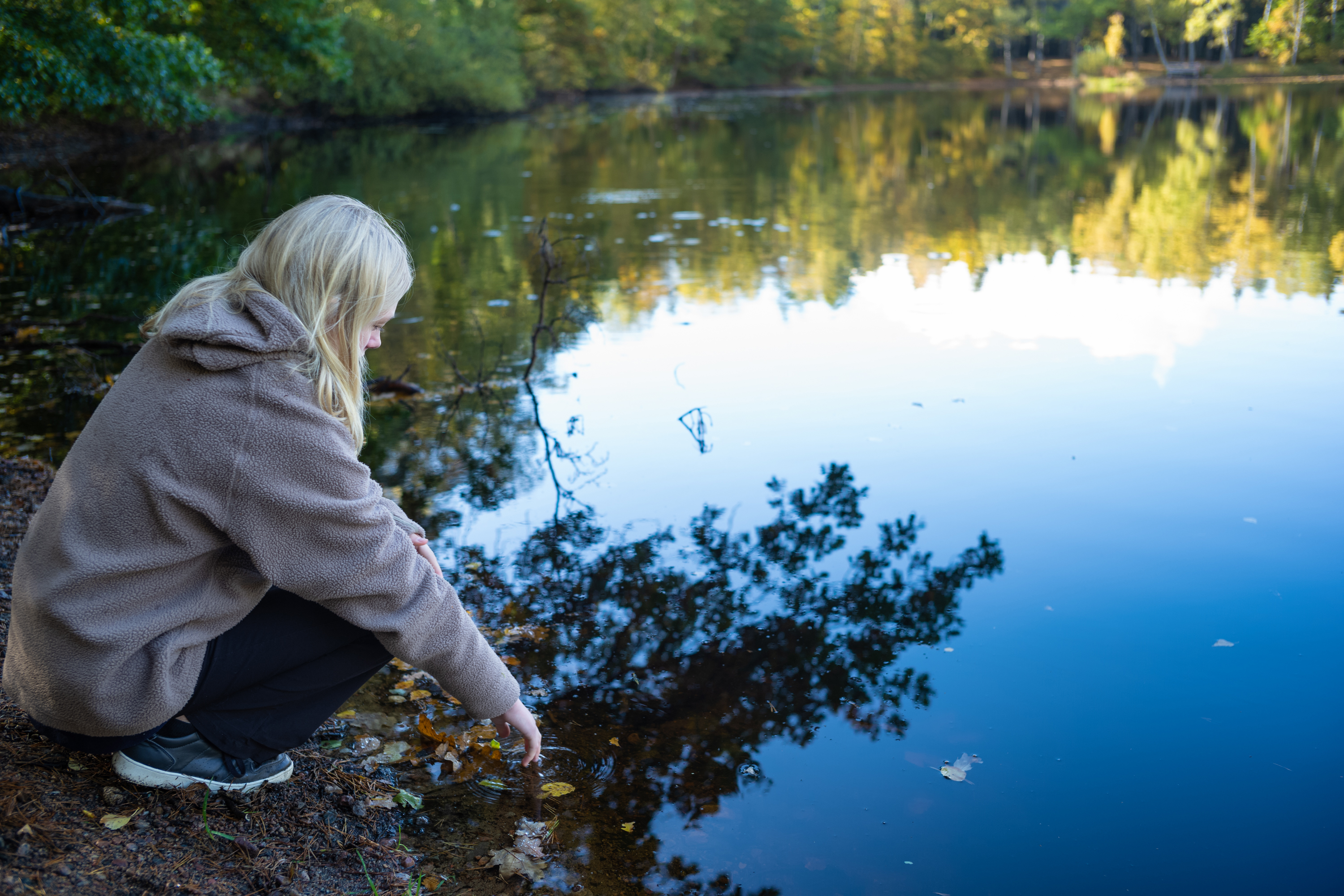 Ta en paus i naturen, i till exempel Vedema strövområde. Tonårstjej sitter vid vattenbrynet